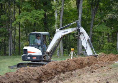 J & J Septic & Sewer team with Bobcat machine is working on the path clearing