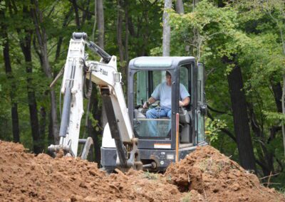 J & J Septic & Sewer team with Bobcat machine is working on the path clearing